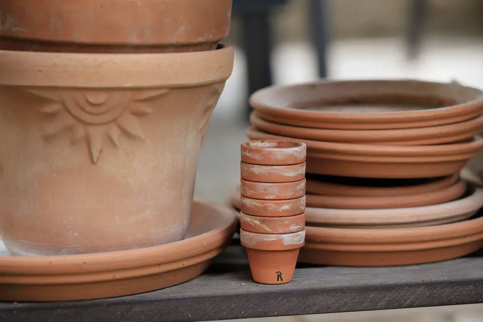 Terracotta pots and matching saucers stacked on a wooden shelf